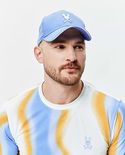 Mens Blaze Sport Cap, a light blue mesh cap with white embroidered Psycho Bunny logo. White pique long-sleeve t-shirt with blue/orange gradient stripes and small blue embroidered Psycho Bunny chest logo. (1)