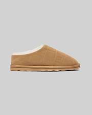 Mens Gio Suede Shearling Slippers in tan suede with plush white shearling lining, featuring an all-over debossed Psycho Bunny skull logo in a diamond grid pattern.