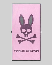 The MENS CLASSIC BUNNY TOWEL - MO1700004 by Psycho Bunny is a pink rectangular towel featuring a bold skull and crossbones with bunny ears, plus "PSYCHO BUNNY" in large text beneath the design.