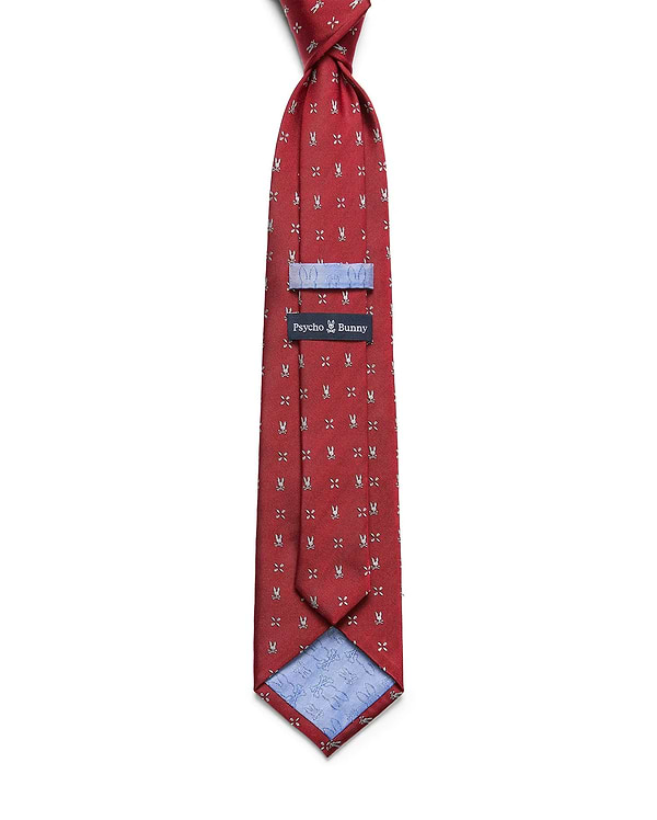 Mens Bunny Neat Woven Tie in red, featuring a repeated silver bunny skull logo pattern, a woven texture, and a light blue lining with a subtle bunny skull print. A black Psycho Bunny label is visible.