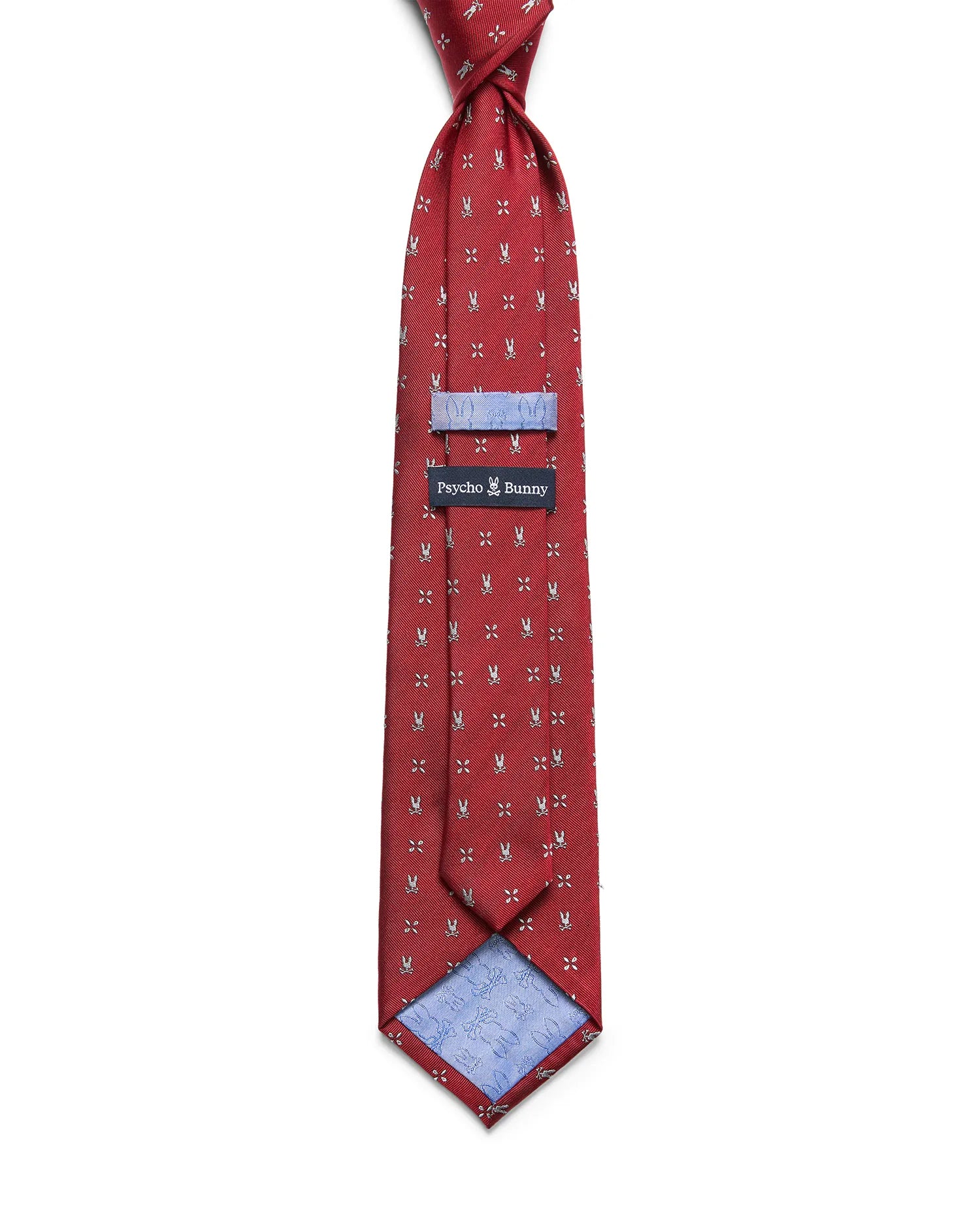 Mens Bunny Neat Woven Tie in red, featuring a repeated silver bunny skull logo pattern, a woven texture, and a light blue lining with a subtle bunny skull print. A black Psycho Bunny label is visible.
