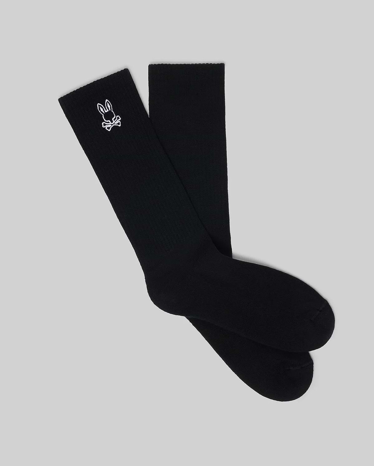 Mens New Classic Sport Sock, premium black ribbed knit crew socks featuring a small, crisp white embroidered Psycho Bunny skull logo prominently on the outer ankle cuff. (1)