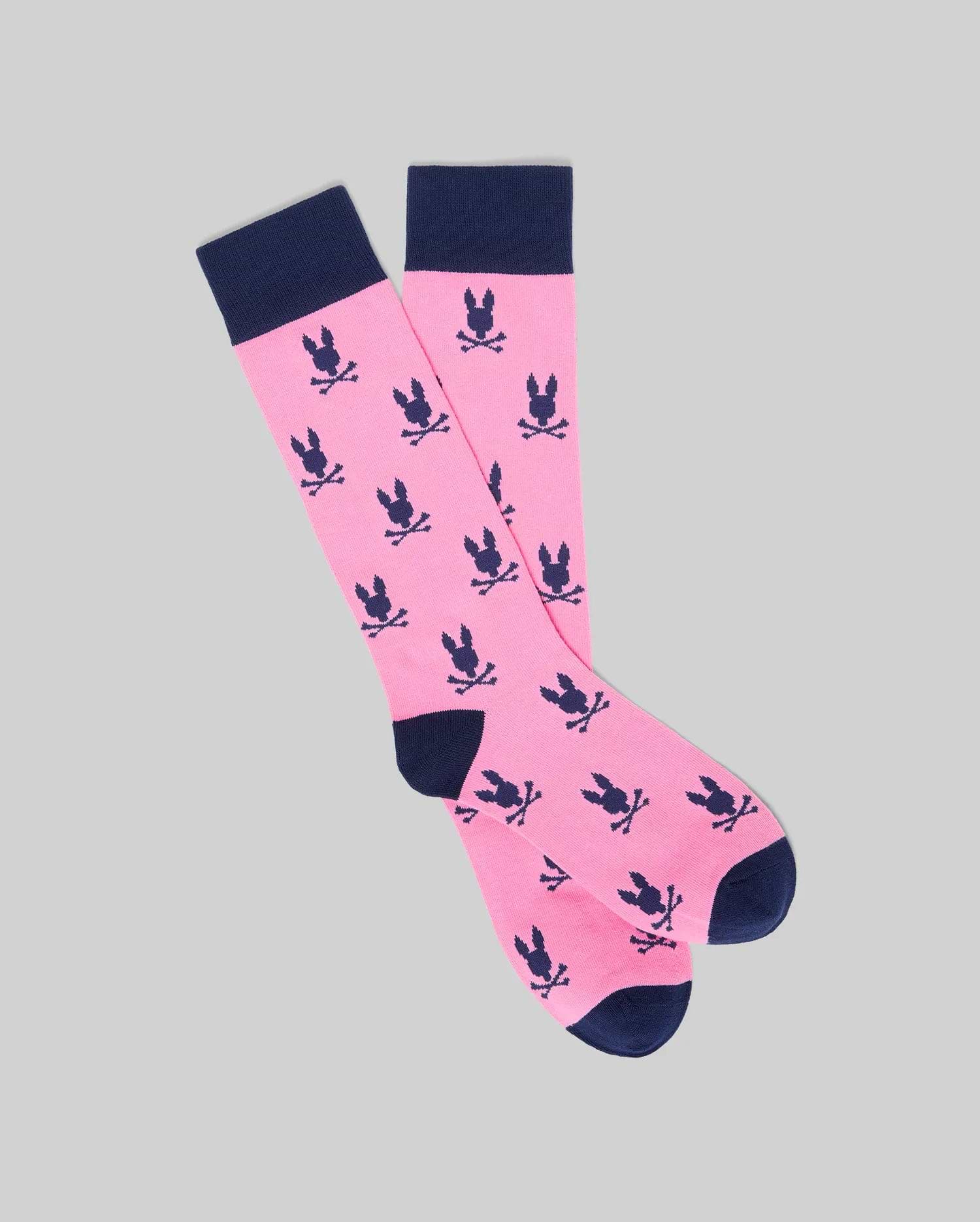 Mens All Over Bunny Dress Sock in vibrant pink with an all-over navy blue Psycho Bunny skull and crossbones pattern, featuring navy cuffs, heels, and toes.