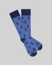 Mens All Over Bunny Dress Sock in medium blue, featuring a seamless all-over dark navy Psycho Bunny skull logo pattern and solid navy cuffs, heels, and toes.