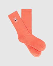 Mens Sunny Sport Sock in vibrant coral ribbed knit, featuring a small embroidered Psycho Bunny skull logo with blue sunglasses and white crossbones on the upper cuff.