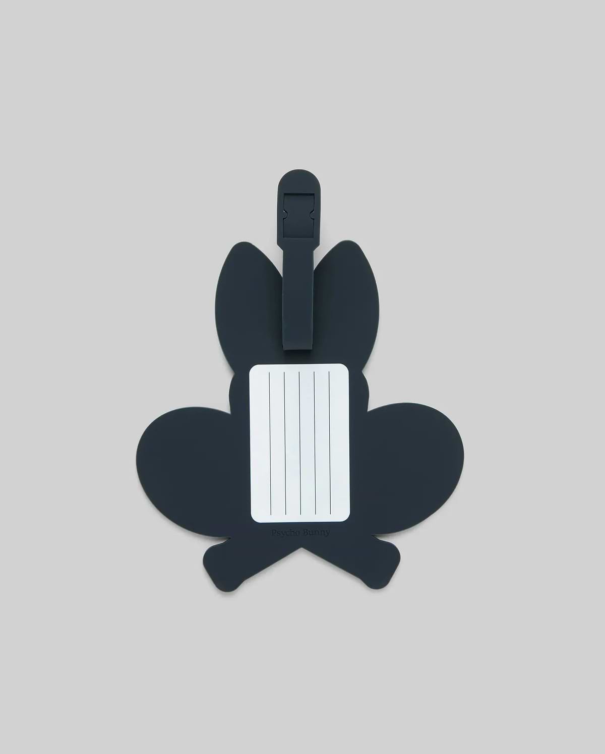 The Psycho Bunny MENS RACKET BUNNY LUGGAGE TAG (MO2400003) features a dark, bunny-shaped silicone design with a white info label and simple strap, shown on a plain light gray background. (2)
