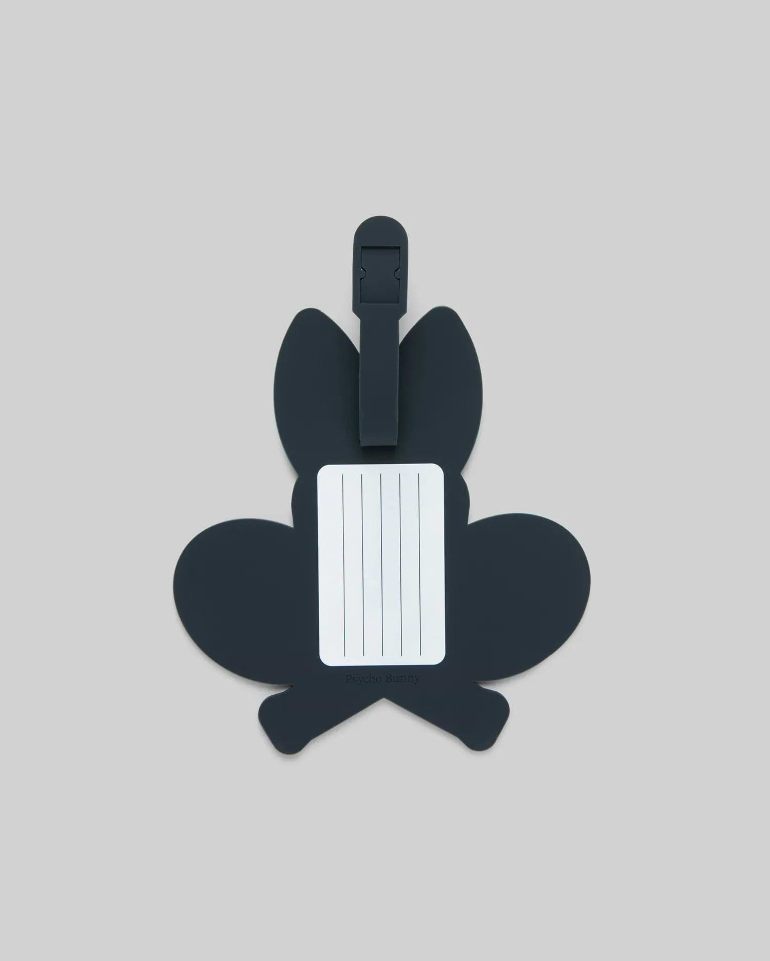 The Psycho Bunny MENS RACKET BUNNY LUGGAGE TAG (MO2400003) features a dark, bunny-shaped silicone design with a white info label and simple strap, shown on a plain light gray background. (2)