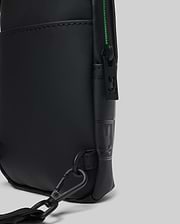 Mens Rubberized Crossbody in black with a smooth matte finish, featuring a vibrant green zipper, black metal hardware, a Psycho Bunny logo zipper pull, and an embossed logo pattern on the side.