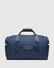 Classic Bunny Gym Bag in navy blue, featuring smooth matte material, white side stripes, and prominent Psycho Bunny text branding on the woven carry straps.