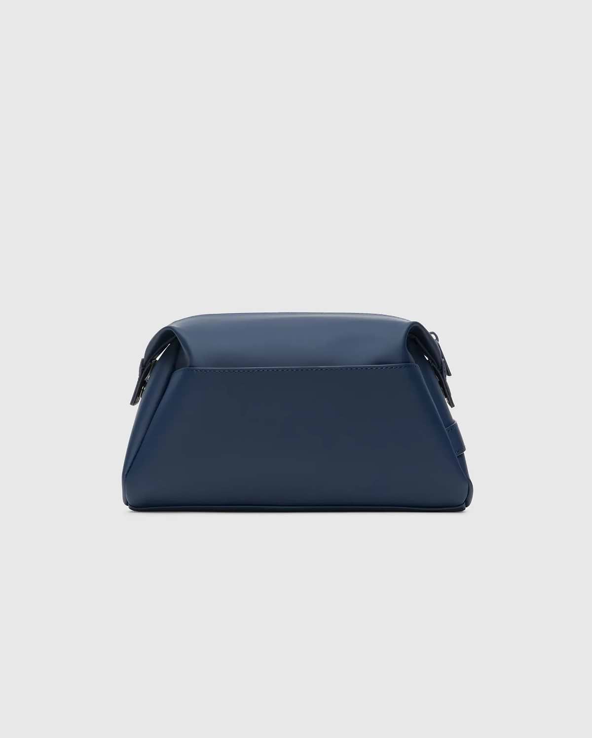 CLASSIC BUNNY TOILETRY KIT, a sleek navy blue travel bag with a smooth, matte finish. It features a structured rectangular shape, rounded edges, and a secure top flap closure, embodying refined streetwear style.