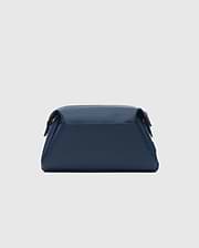 CLASSIC BUNNY TOILETRY KIT, a sleek navy blue travel bag with a smooth, matte finish. It features a structured rectangular shape, rounded edges, and a secure top flap closure, embodying refined streetwear style.