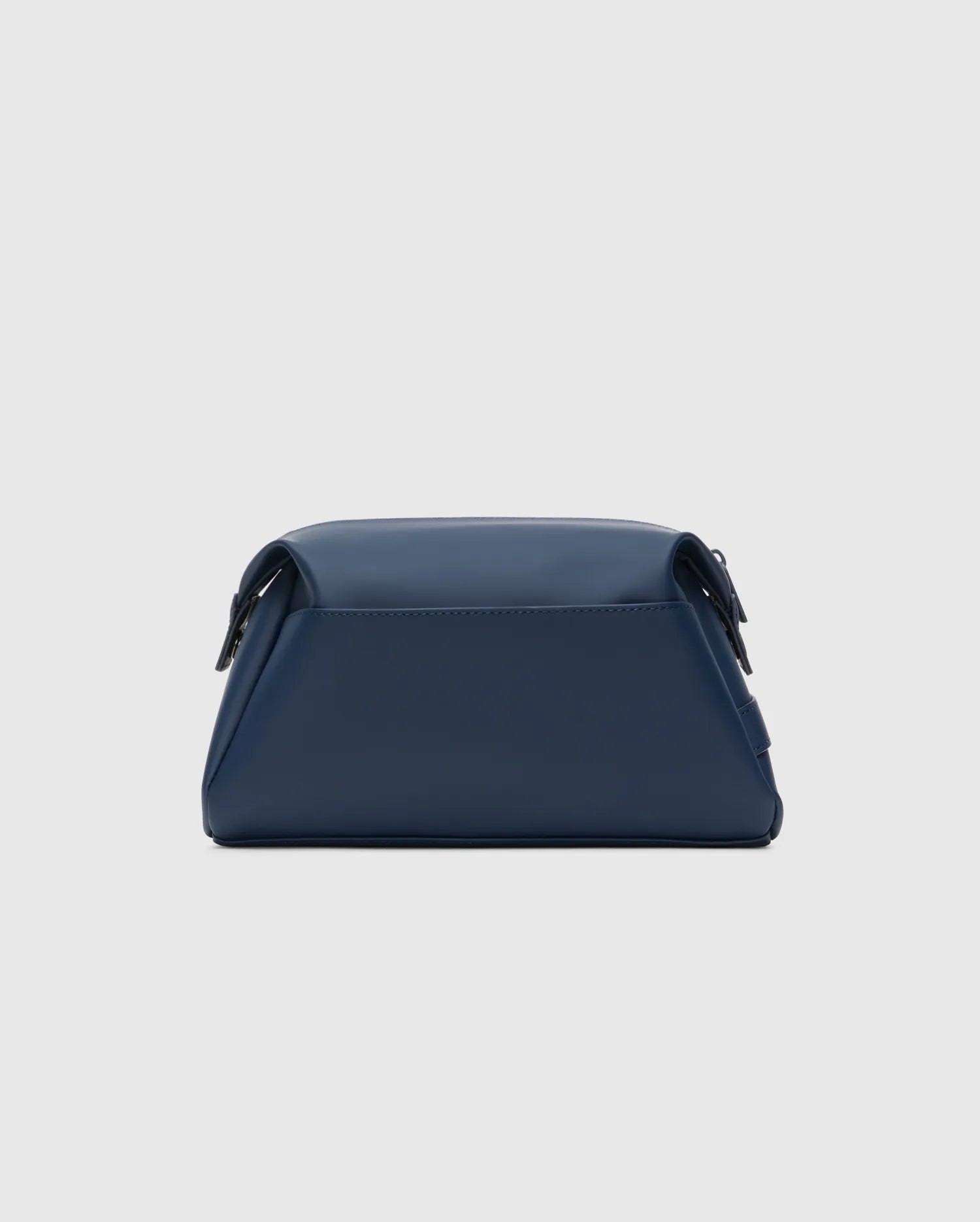 CLASSIC BUNNY TOILETRY KIT, a sleek navy blue travel bag with a smooth, matte finish. It features a structured rectangular shape, rounded edges, and a secure top flap closure, embodying refined streetwear style.