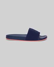 Mens Contrast Sole Knit Slides, premium Psycho Bunny footwear, in deep navy with a textured knit strap featuring subtle branding and a vibrant coral contrast sole for refined streetwear style.