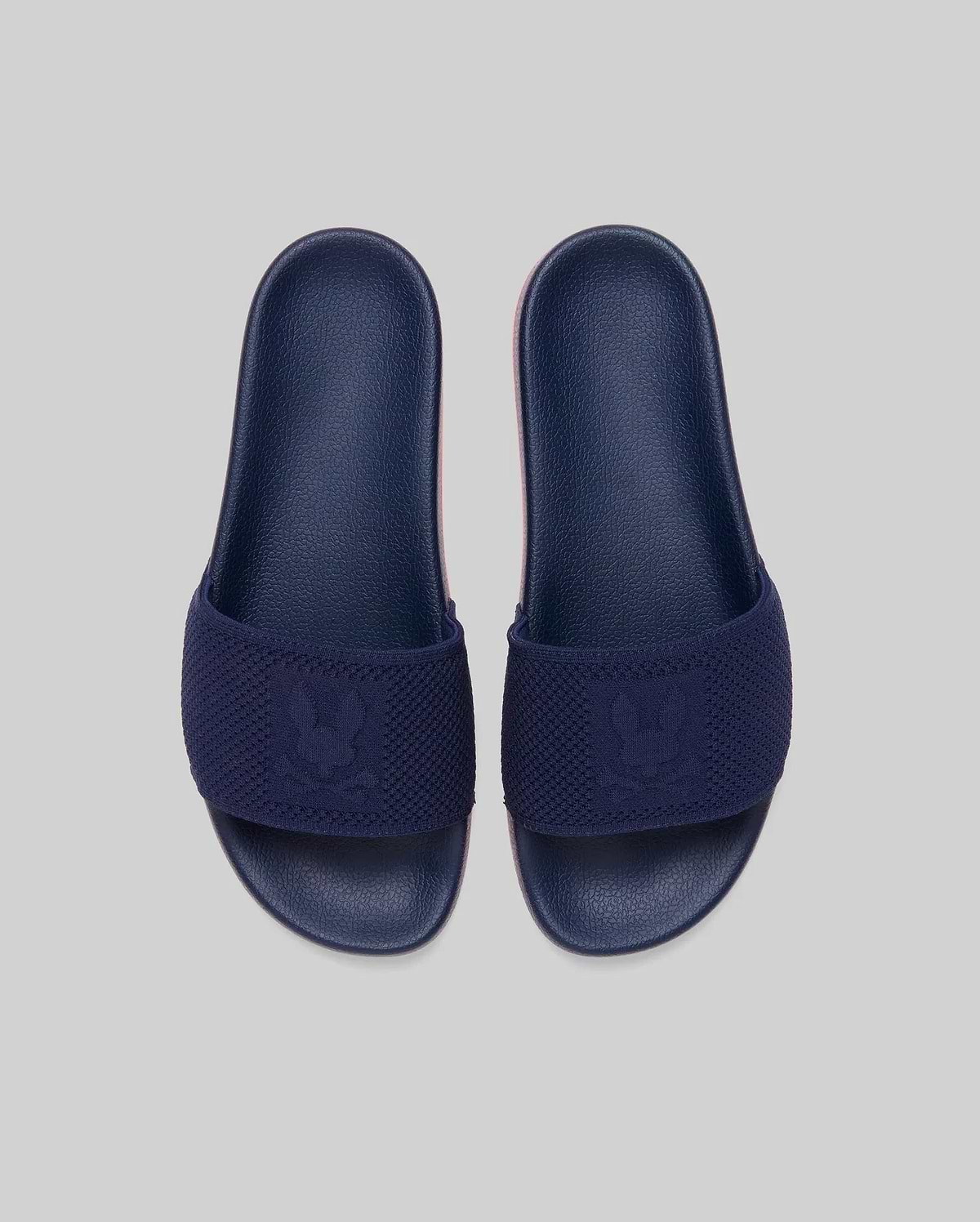 Mens Contrast Sole Knit Slides in navy with a textured knit strap featuring a woven Psycho Bunny skull logo and a subtle pink contrast sole.