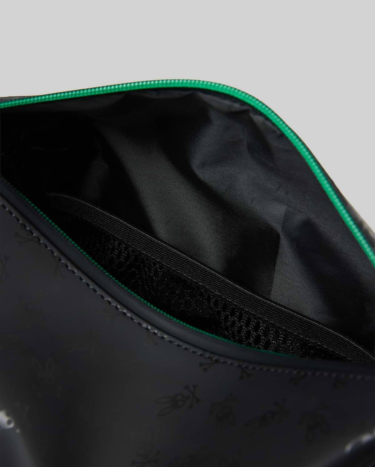 Mens All Over Bunny Toiletry Kit in black with a subtle all-over Psycho Bunny skull logo print, vibrant green zipper, smooth exterior, and an internal mesh pocket.