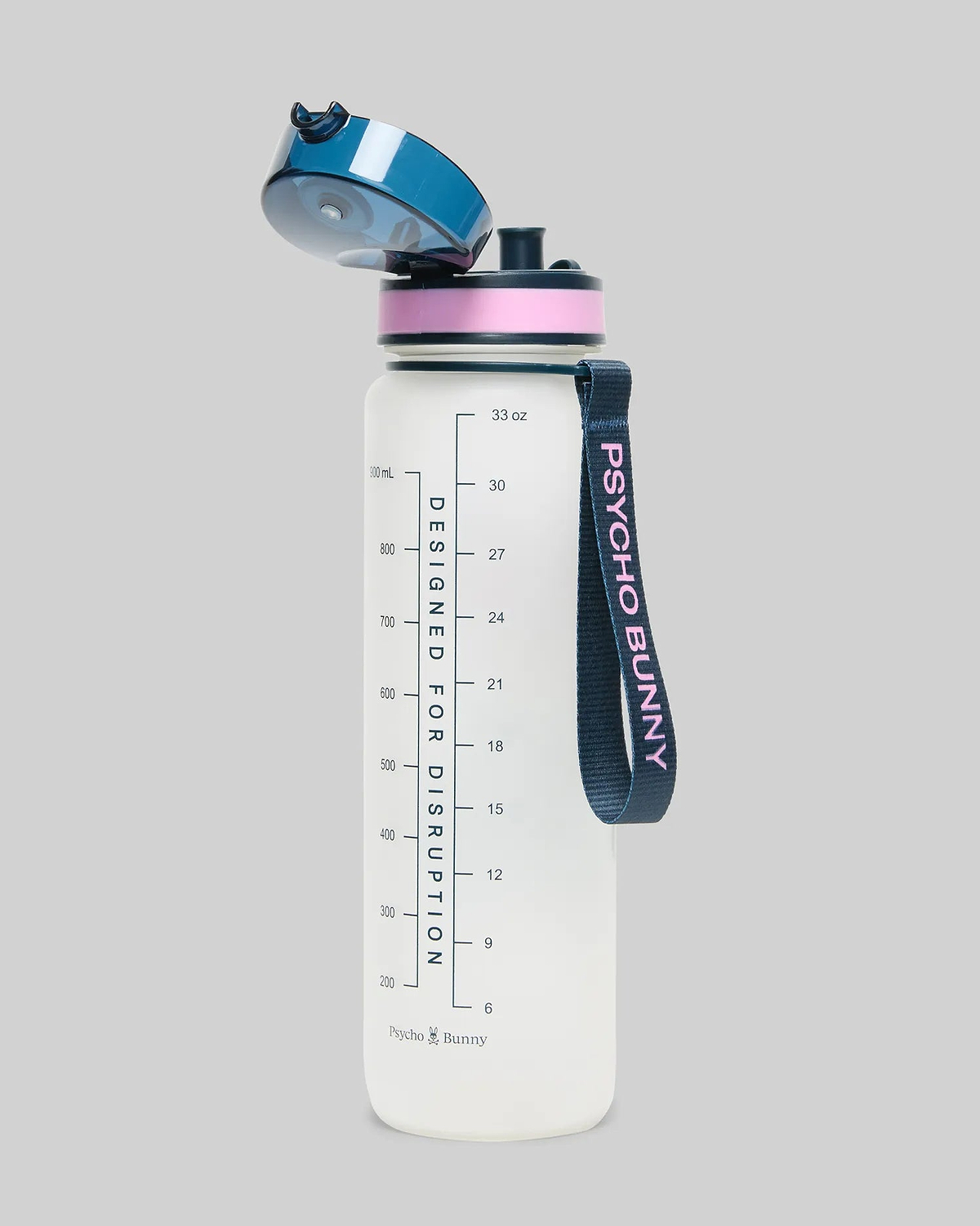 33 Oz Water Bottle, translucent white with a dark blue flip-top lid, pink accent ring, and a dark blue strap featuring pink Psycho Bunny text. It has measurement markings and Designed For Disruption text.