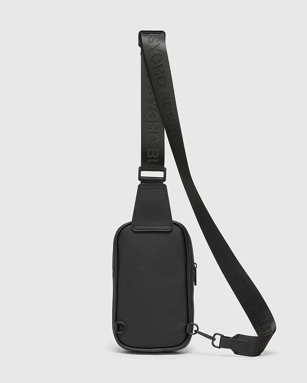 Black Crossbody Bag featuring a durable textured material, an adjustable strap with embossed Psycho Bunny logo text, a secure top zipper, and sleek black metal hardware. (4)