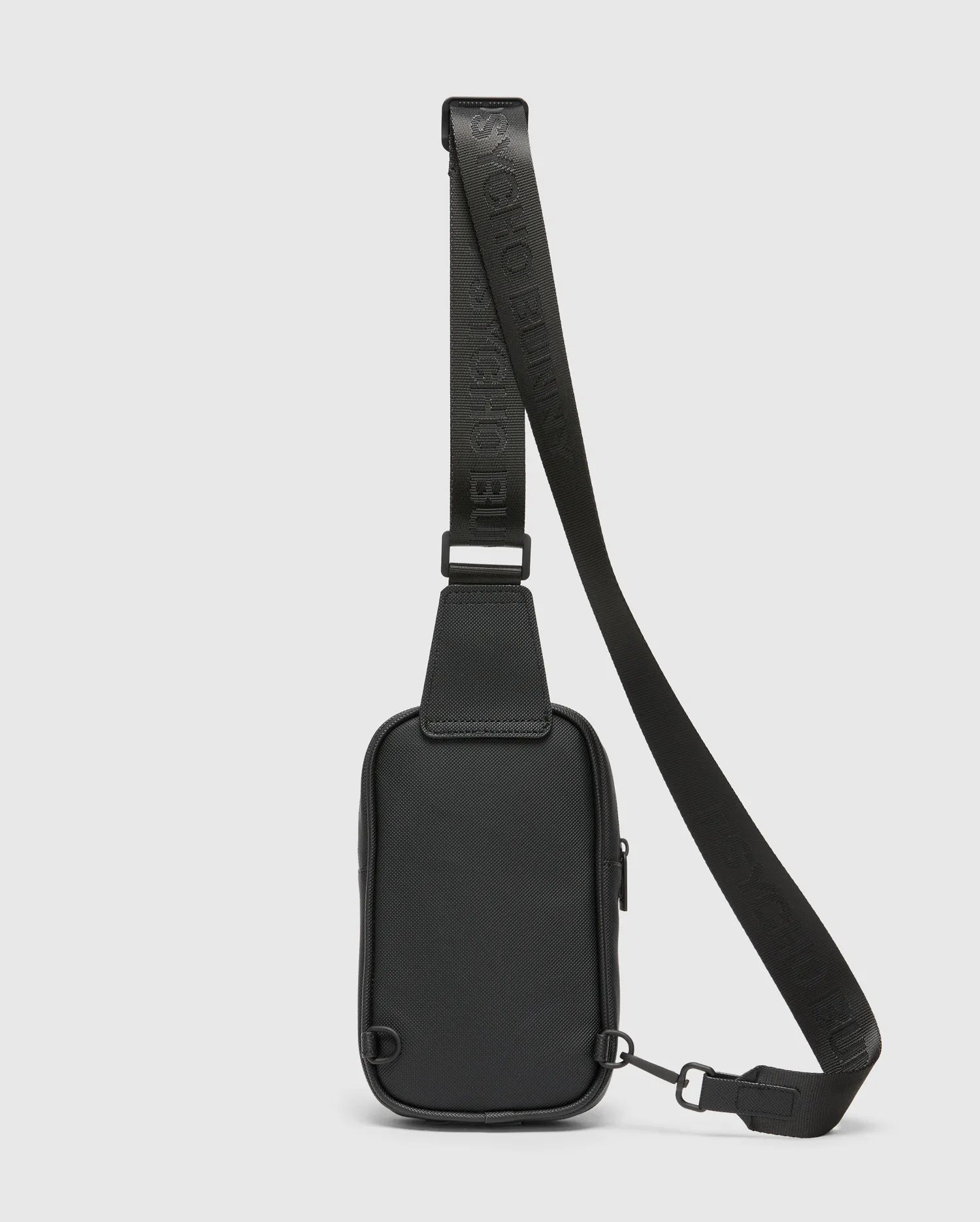Black Crossbody Bag featuring a durable textured material, an adjustable strap with embossed Psycho Bunny logo text, a secure top zipper, and sleek black metal hardware. (4)