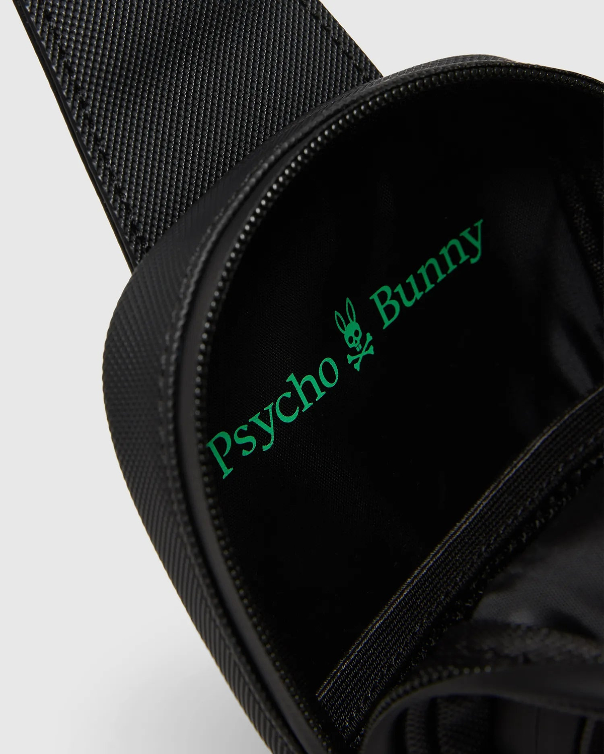 Black textured Crossbody Bag with a bright green Psycho Bunny logo and text printed large inside the main compartment, featuring a durable zipper closure. (2)