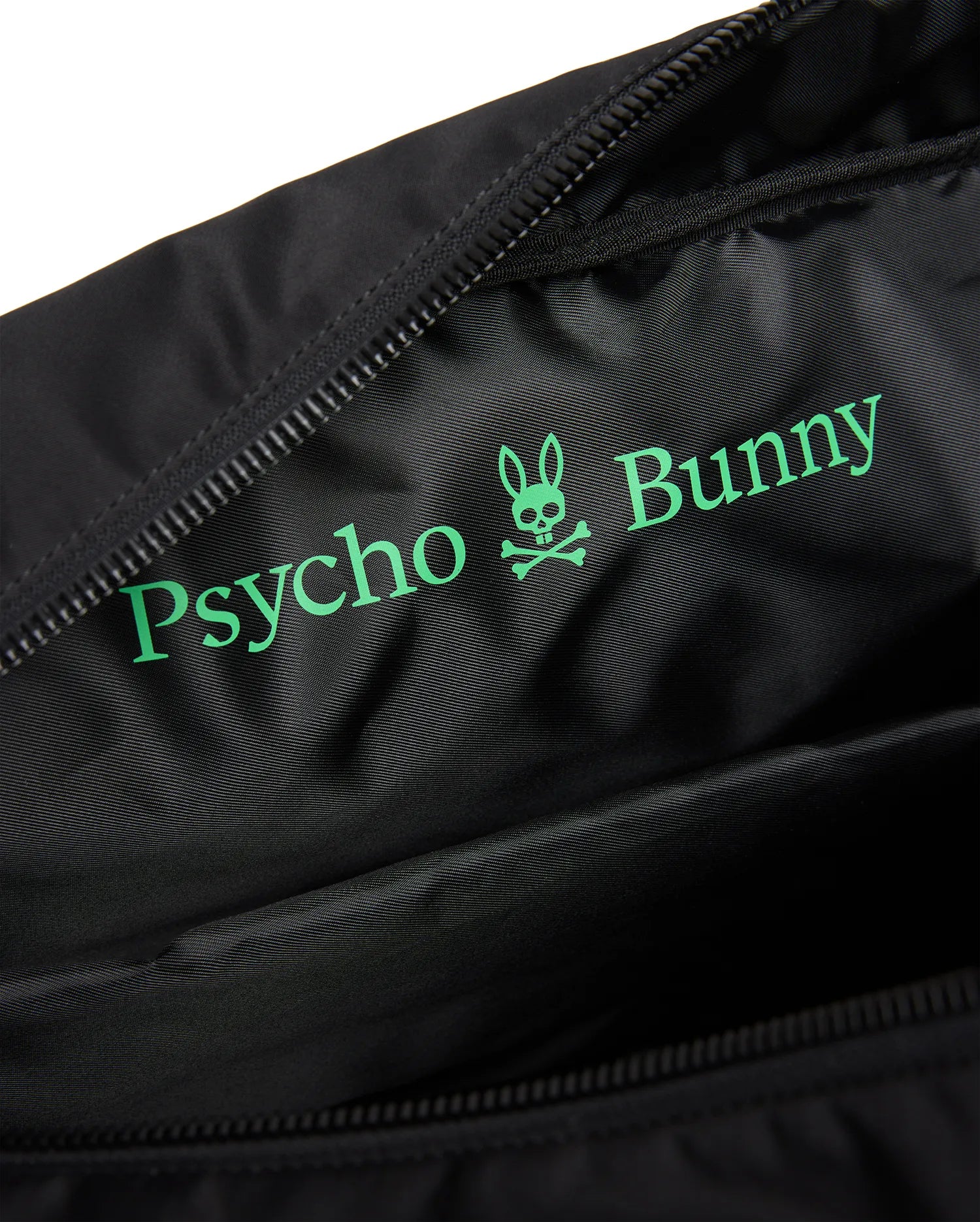 Black Mens Nylon Duffle Bag interior with a large, vibrant green Psycho Bunny text and iconic skull logo printed on the smooth, subtly textured nylon lining, next to a black zipper. (3)