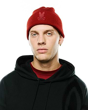 Red ribbed knit Men's Leighton Merino Beanie with tonal embroidered Psycho Bunny skull logo, paired with a black relaxed fit French terry hoodie featuring a subtle graphic print and a red crewneck t-shirt. (1)