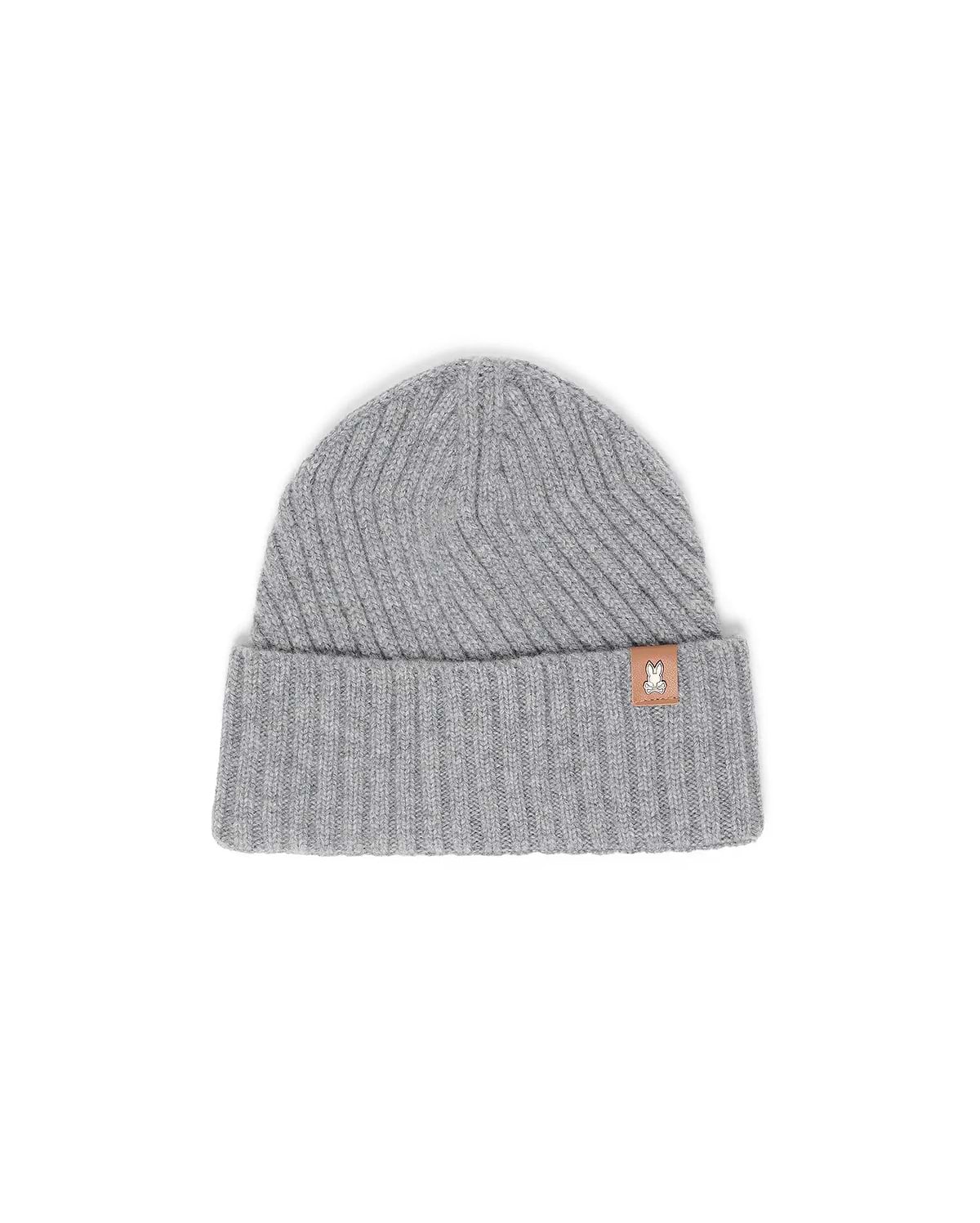 Mens Brogan Beanie, a grey ribbed knit beanie with a classic fit and a folded cuff, featuring a small brown leather-like patch on the front cuff with the iconic white Psycho Bunny skull logo.