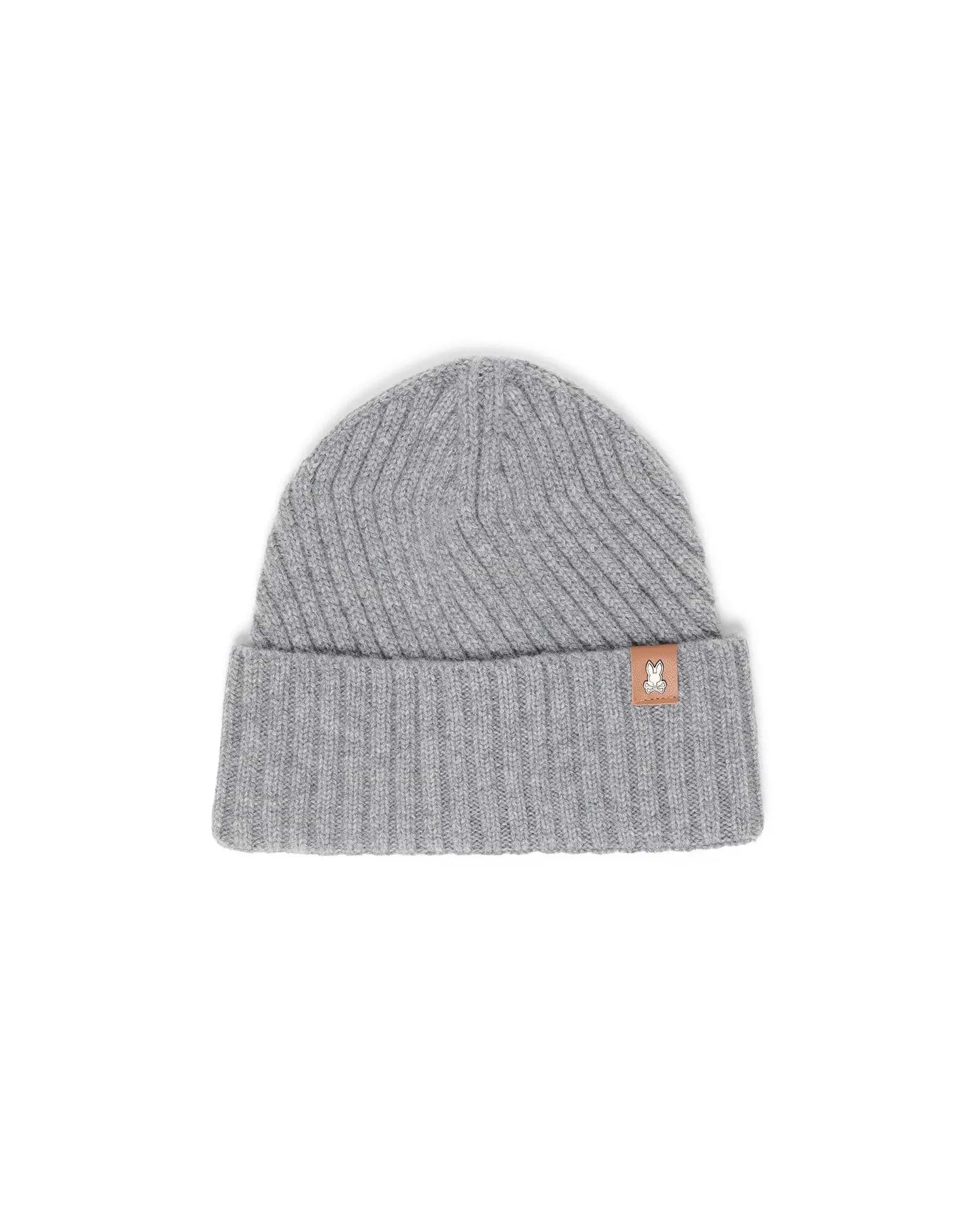 Mens Brogan Beanie, a grey ribbed knit beanie with a classic fit and a folded cuff, featuring a small brown leather-like patch on the front cuff with the iconic white Psycho Bunny skull logo.
