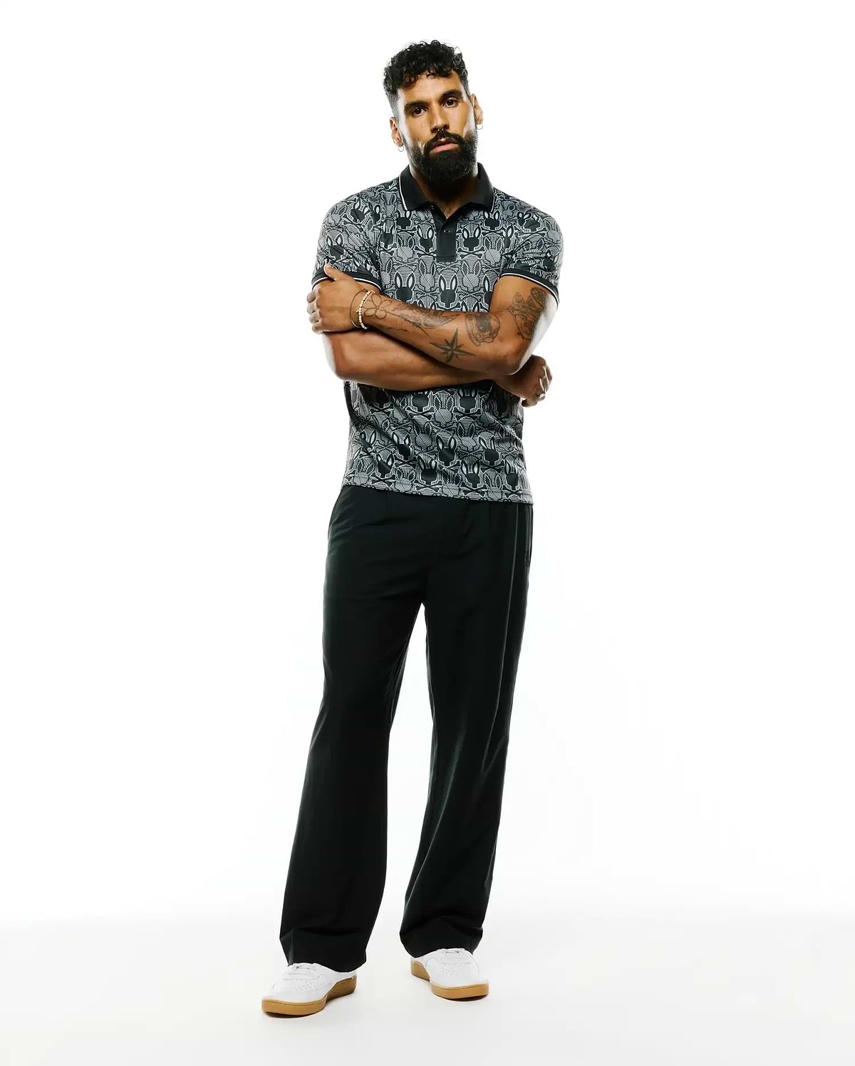 Mens Reeves All Over Bunny Sport Polo, a classic fit black and grey pique polo featuring an all-over white bunny skull pattern and crisp white trim on the collar and sleeves.