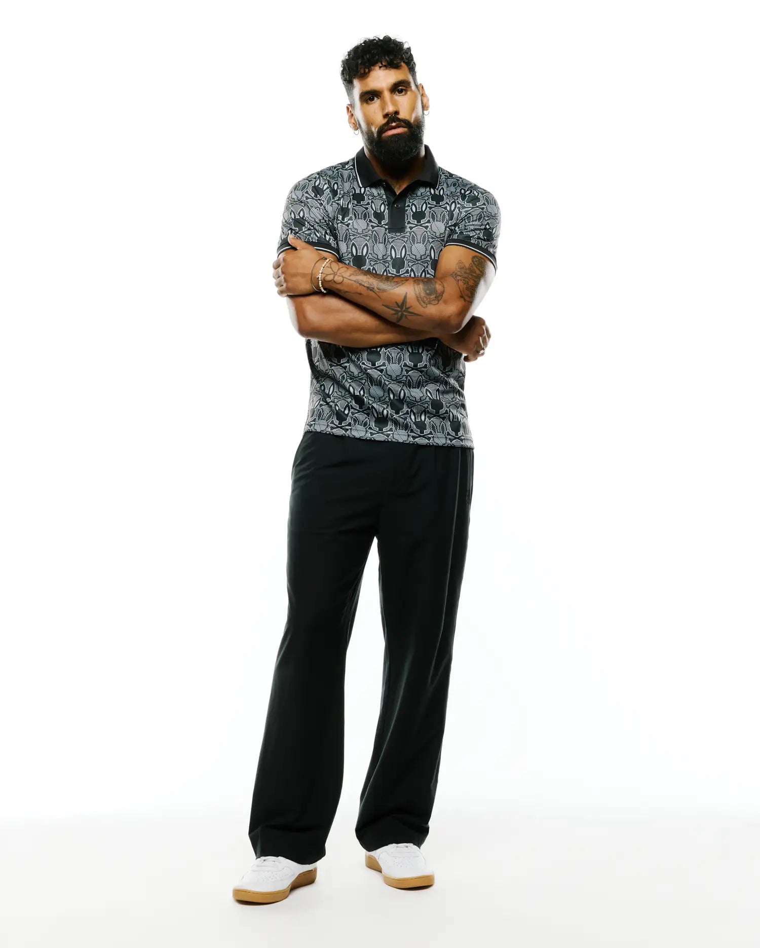 Mens Reeves All Over Bunny Sport Polo, a classic fit black and grey pique polo featuring an all-over white bunny skull pattern and crisp white trim on the collar and sleeves.
