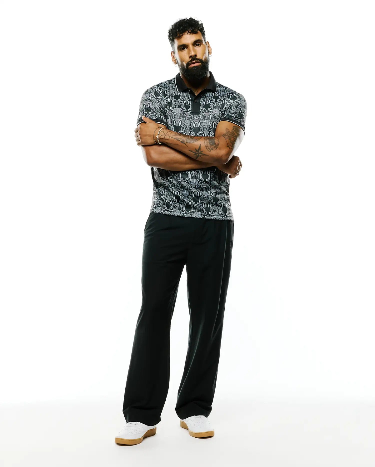 Mens Reeves All Over Bunny Sport Polo, a classic fit black and grey pique polo featuring an all-over white bunny skull pattern and crisp white trim on the collar and sleeves.