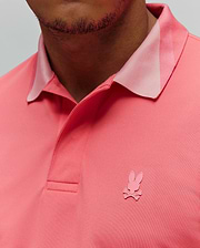 Mens Onyx Sport Polo in vibrant coral pique knit, classic fit, featuring a lighter pink collar accent and a small, embroidered pink Psycho Bunny skull logo on the left chest.