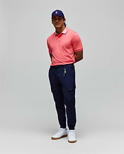 Mens Onyx Sport Polo in coral pique with a lighter pink collar and embroidered chest logo, paired with navy slim-fit cargo joggers featuring a tonal bunny logo and a navy cap with a pink embroidered bunny.