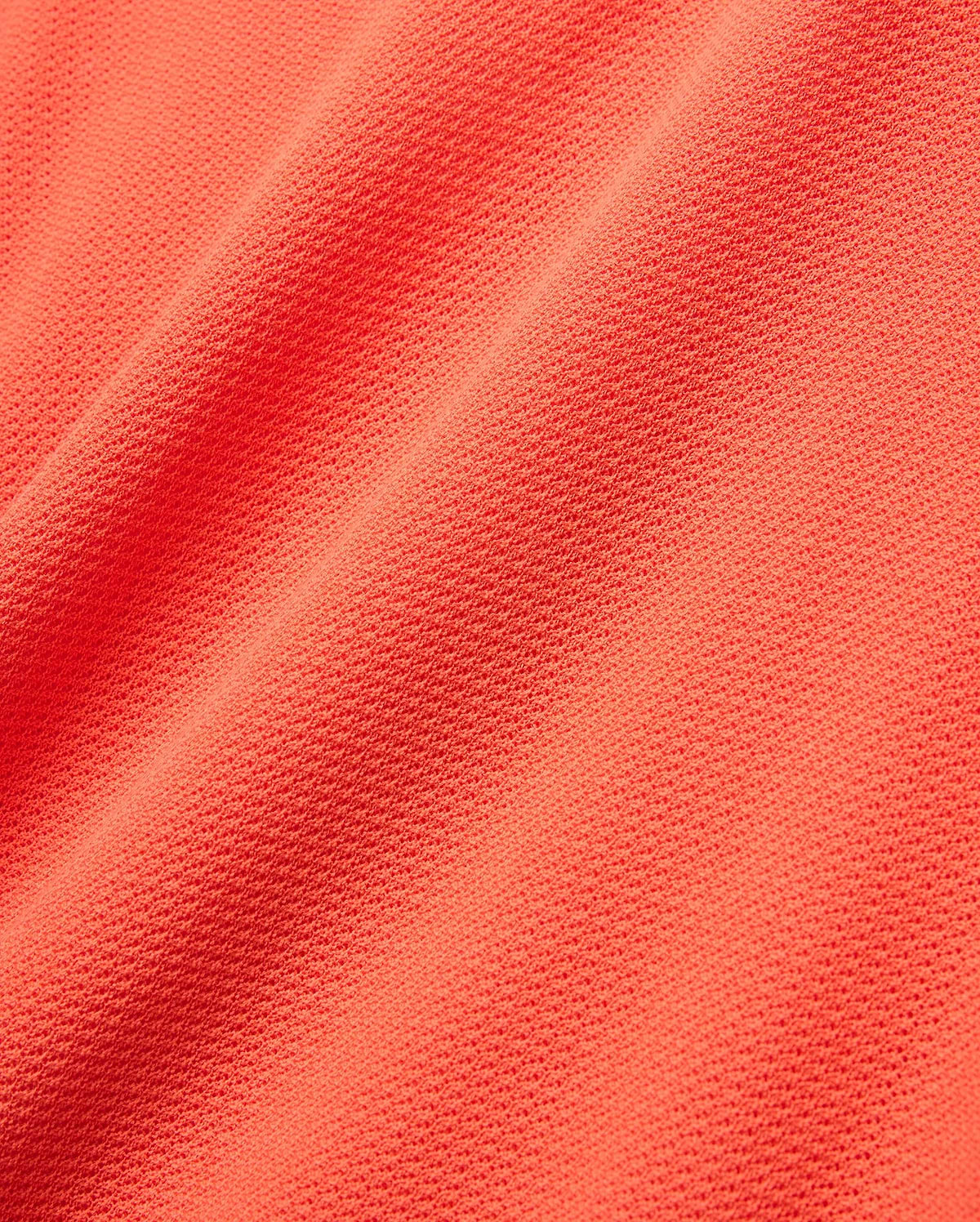 Mens Innis Polo in vibrant coral orange pique knit fabric, showcasing its signature textured, breathable weave with subtle diagonal folds, ideal for premium Psycho Bunny refined streetwear. (5)
