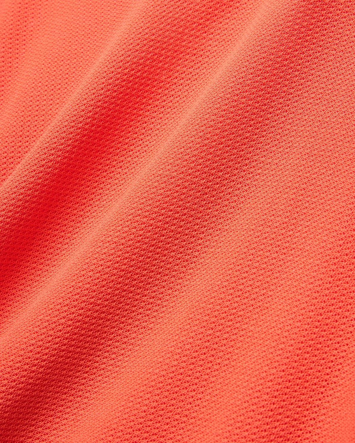 Mens Innis Polo in vibrant coral orange pique knit fabric, showcasing its signature textured, breathable weave with subtle diagonal folds, ideal for premium Psycho Bunny refined streetwear. (5)