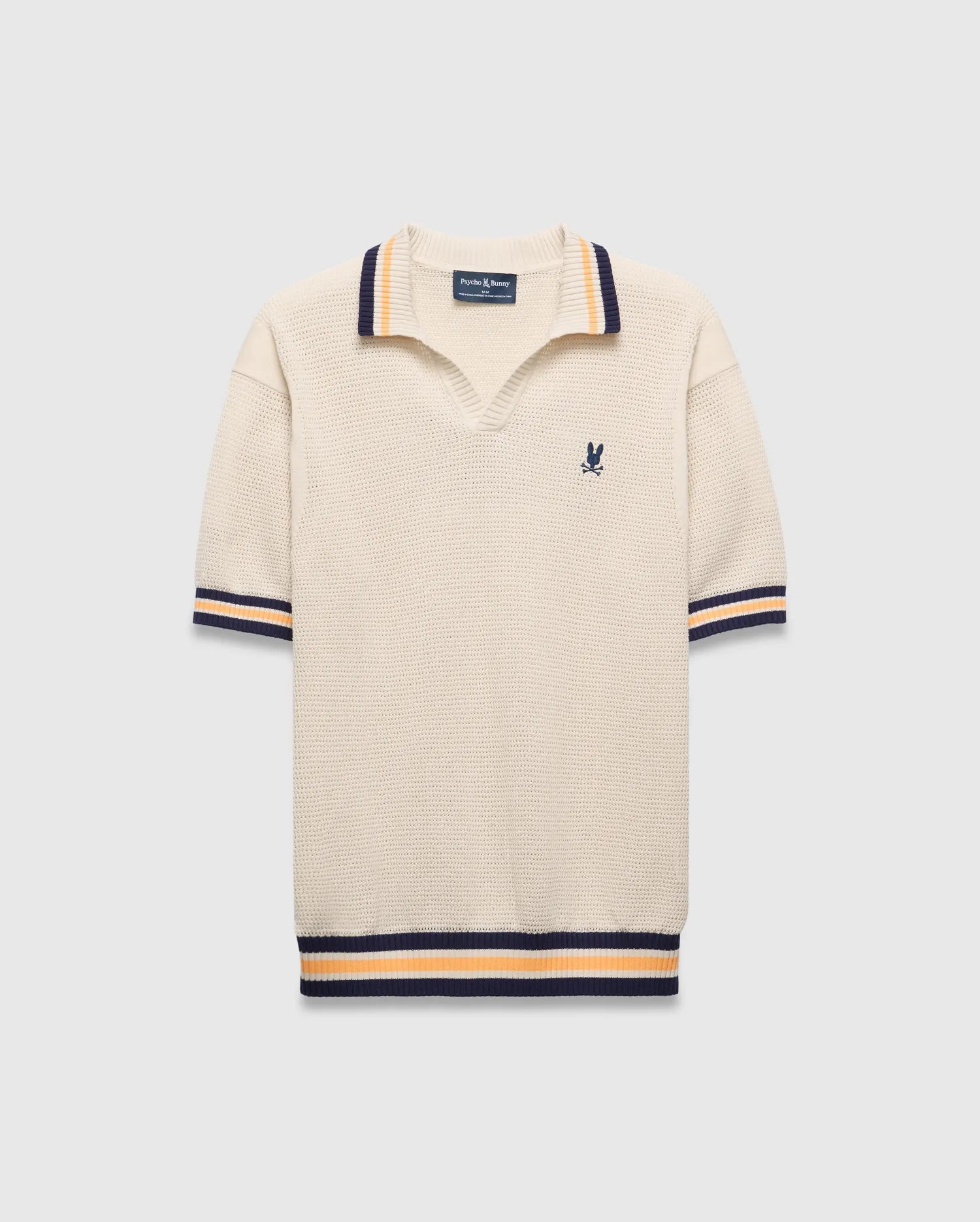 Mens Theros Knit Polo, cream textured knit with a relaxed fit, featuring a V-neck, navy and orange striped ribbed collar, cuffs, and hem, and a small embroidered navy Psycho Bunny skull logo on the left chest.