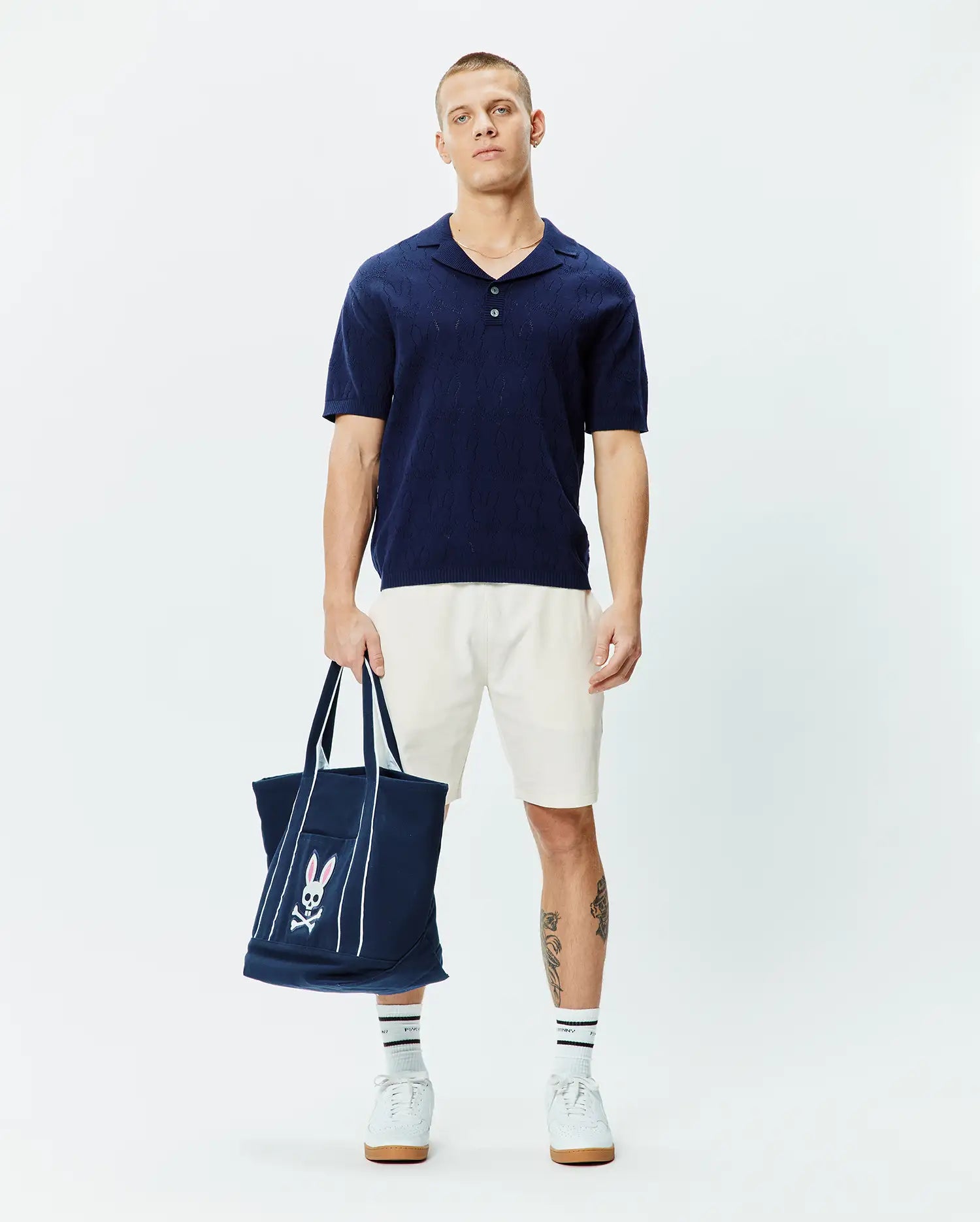 Mens Harold Pointelle All Over Bunny Knit Polo, a navy blue short-sleeve knit polo with a classic fit, featuring an intricate all-over pointelle bunny skull pattern as its distinctive branding.
