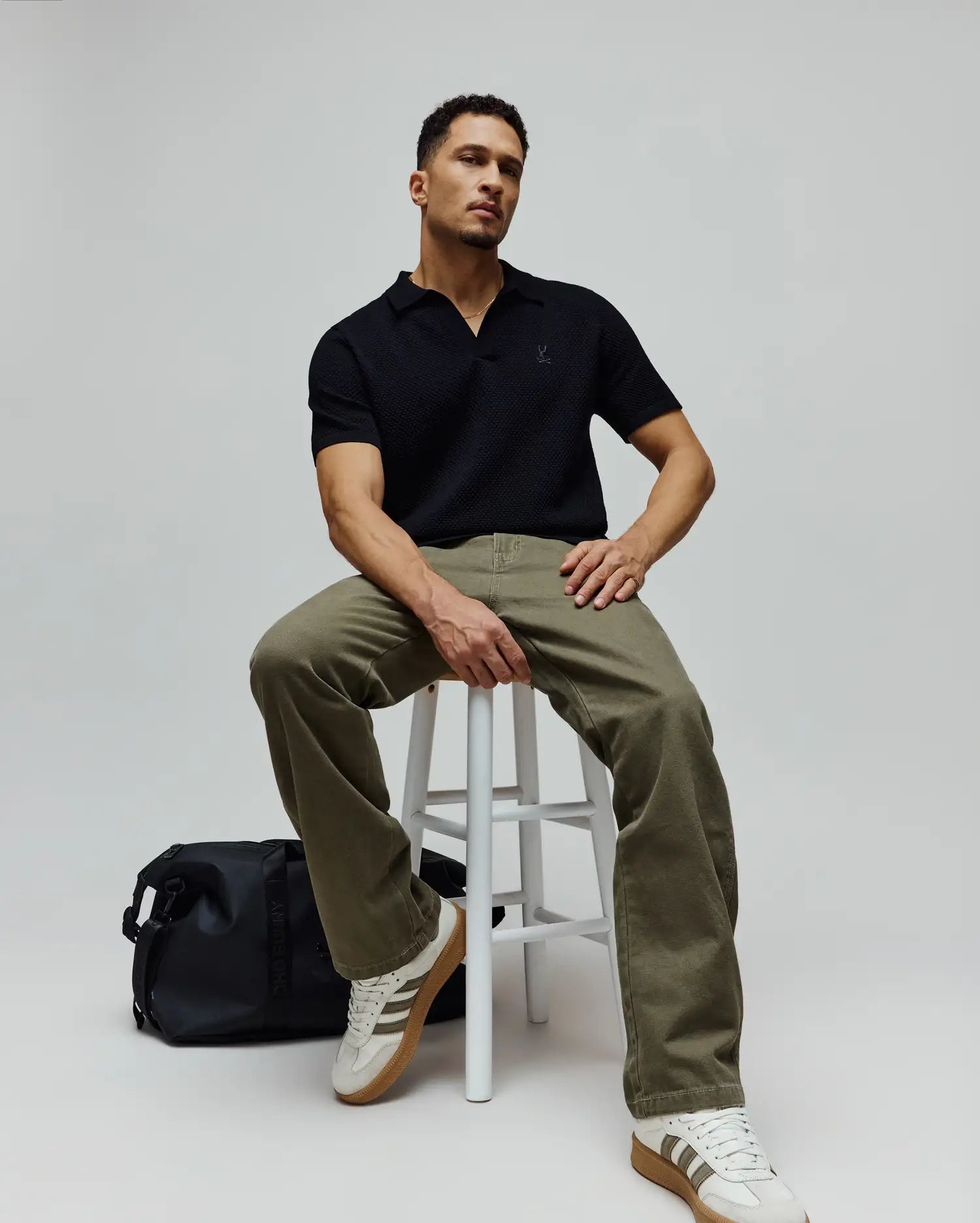 Mens Devon Knit Polo in black, featuring a refined textured knit fabric, an open collar, and a small embroidered Psycho Bunny skull logo on the left chest for a classic fit.