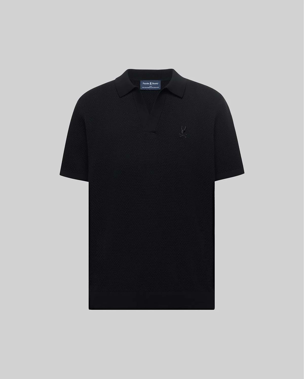 Mens Devon Knit Polo in black, featuring a subtle textured knit, classic fit, V-neck placket, and a tonal embroidered Psycho Bunny skull logo on the left chest.