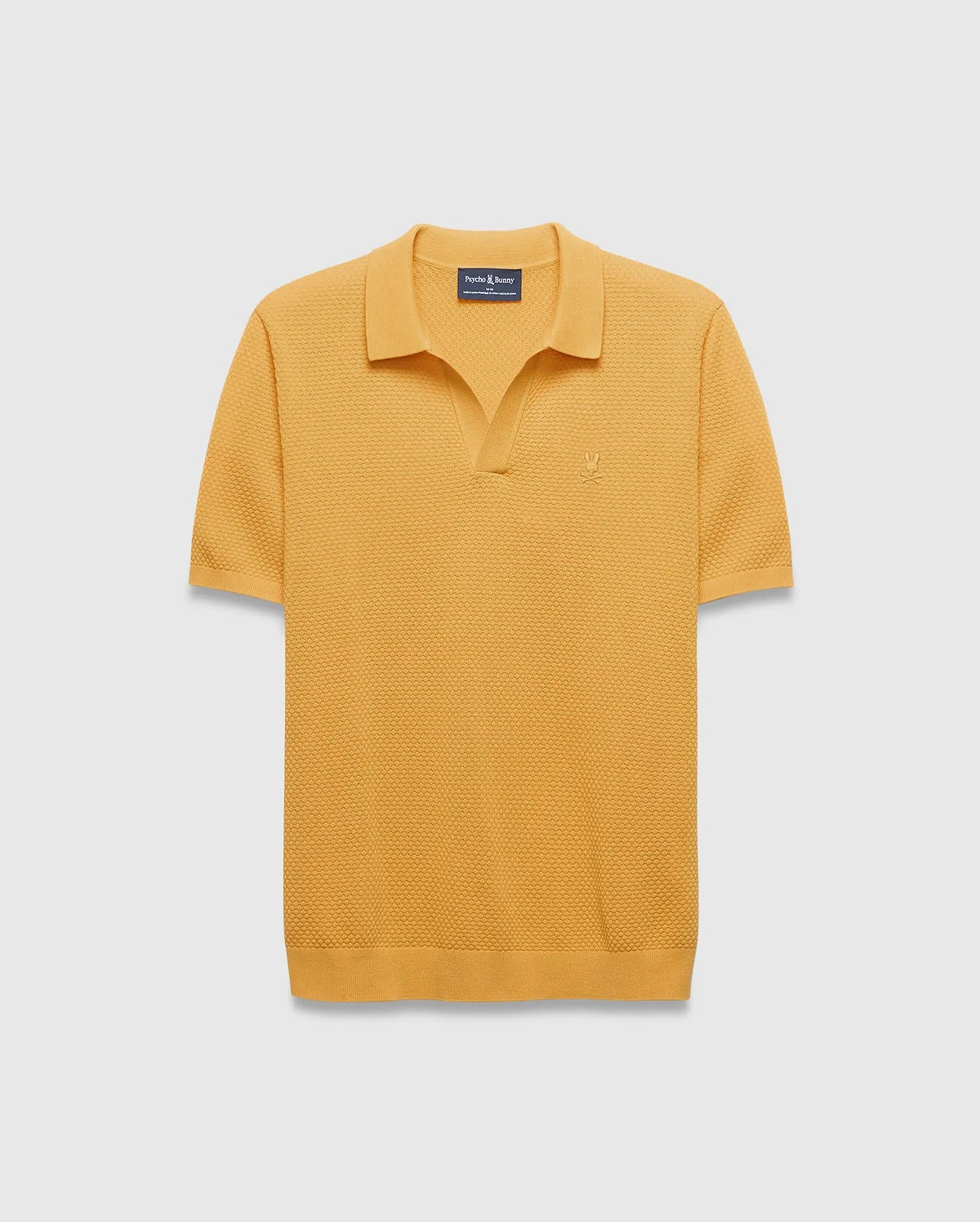 Mens Devon Knit Polo in mustard yellow, featuring a textured waffle knit fabric, classic fit, spread collar, V-neck placket, and a small embroidered Psycho Bunny skull logo on the left chest.
