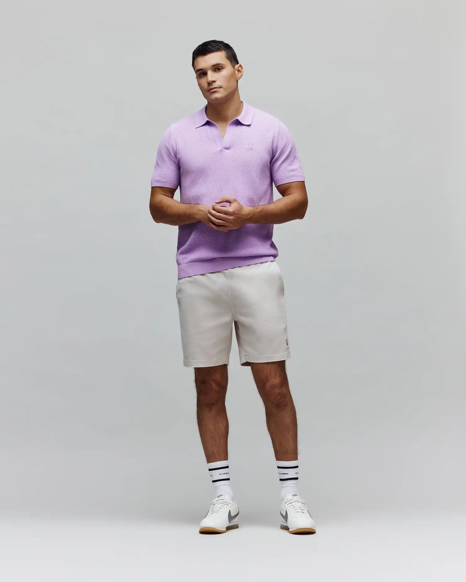 Mens Devon Knit Polo in lavender, featuring a textured knit fabric, open collar, ribbed hem, and a small embroidered Psycho Bunny skull logo on the left chest.
