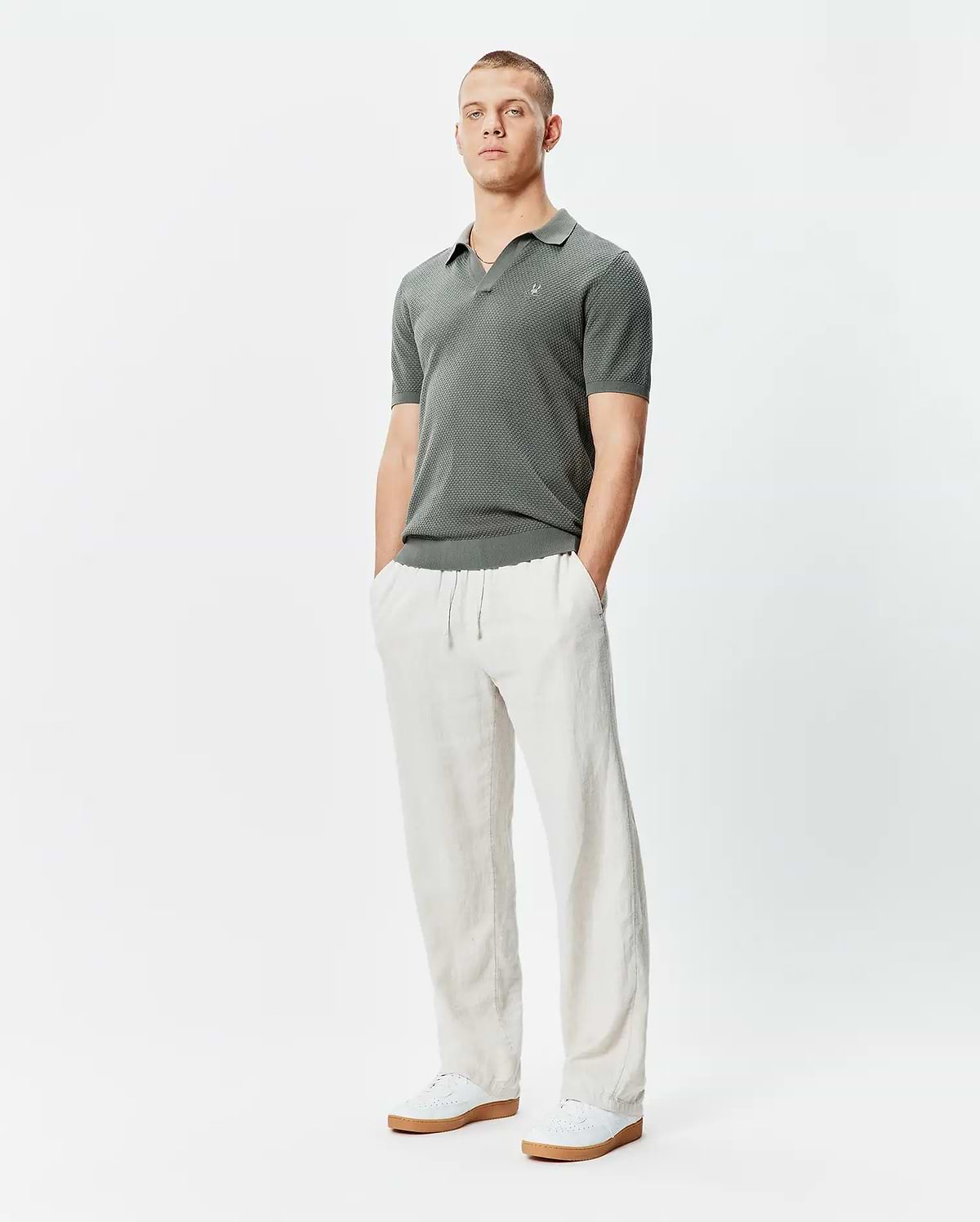 Mens Devon Knit Polo, a classic fit charcoal textured knit polo shirt featuring a subtle geometric pattern and a small embroidered Psycho Bunny skull logo on the left chest.