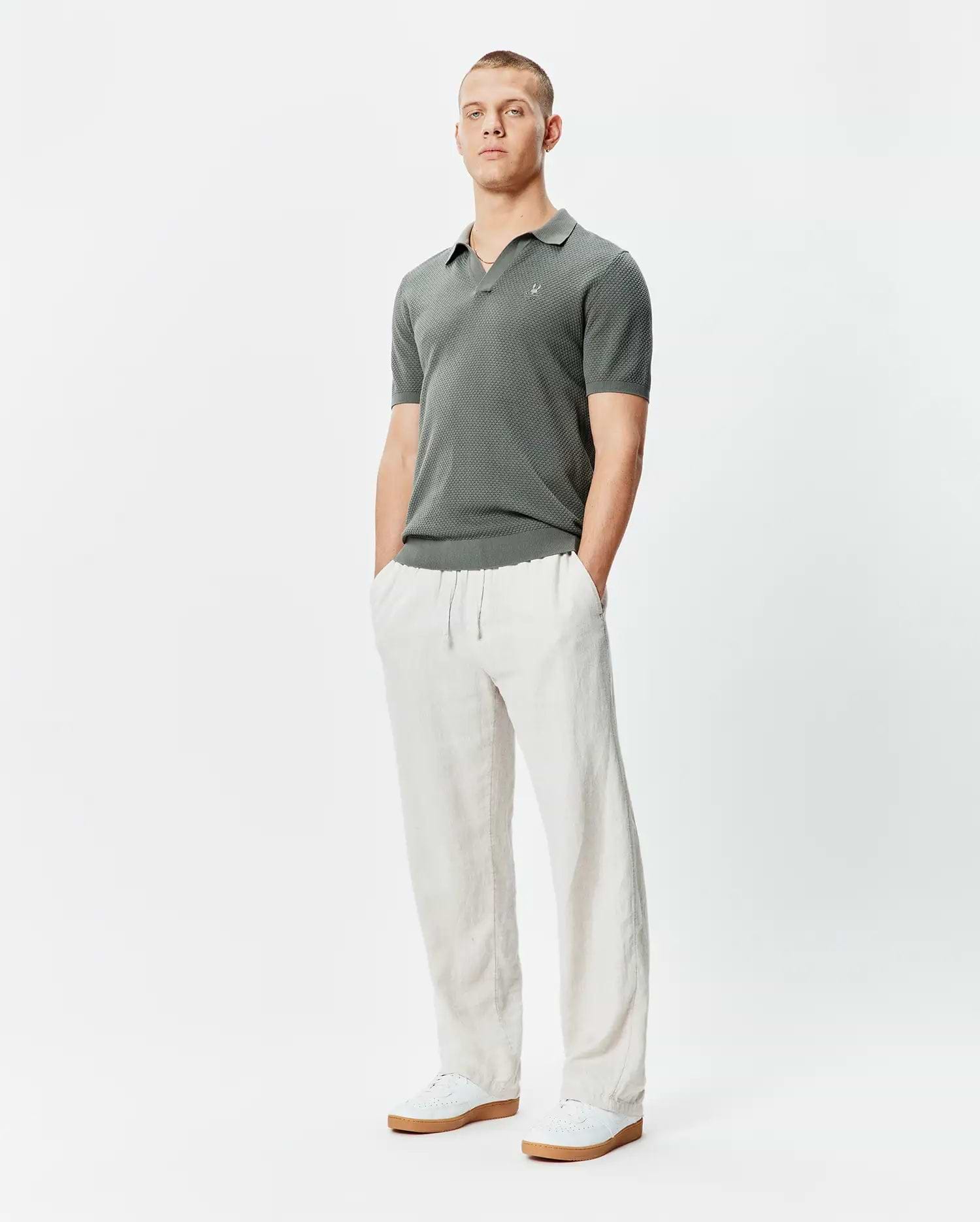 Mens Devon Knit Polo, a classic fit charcoal textured knit polo shirt featuring a subtle geometric pattern and a small embroidered Psycho Bunny skull logo on the left chest.
