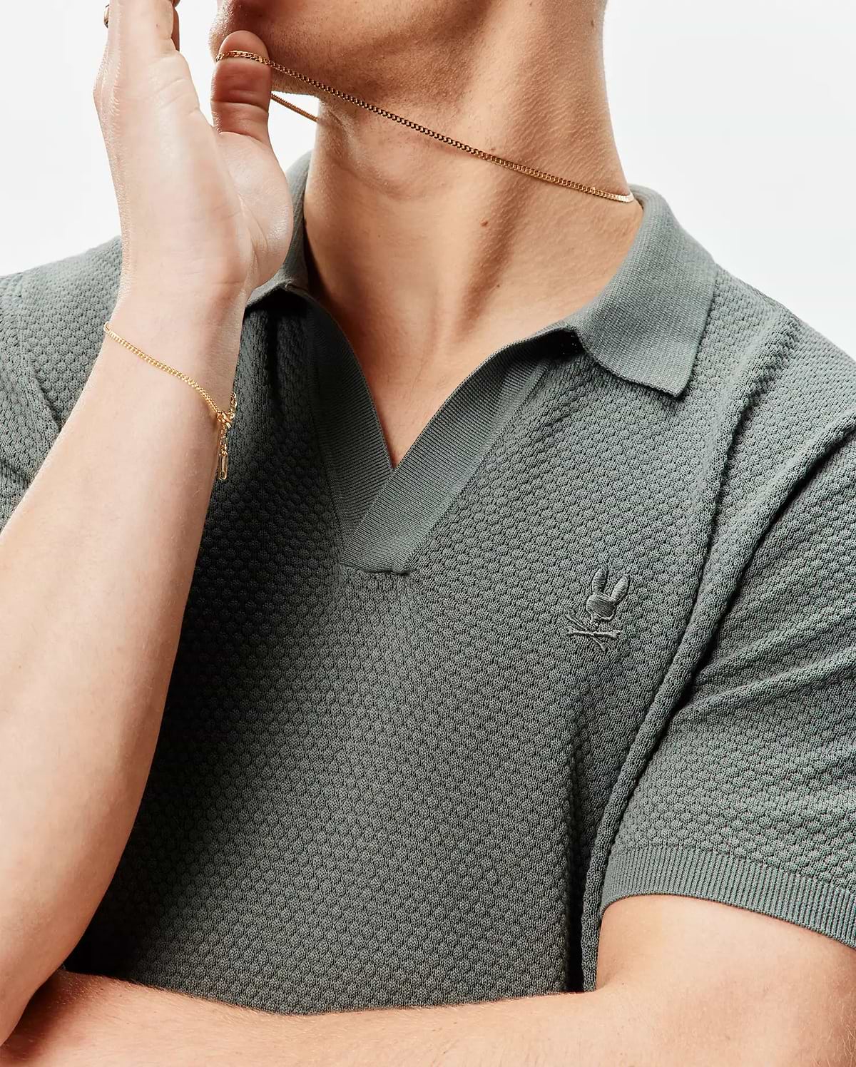Mens Devon Knit Polo in dark sage green, featuring a textured knit fabric, open V-neck collar, and a small, tonal embroidered Psycho Bunny skull logo on the left chest.