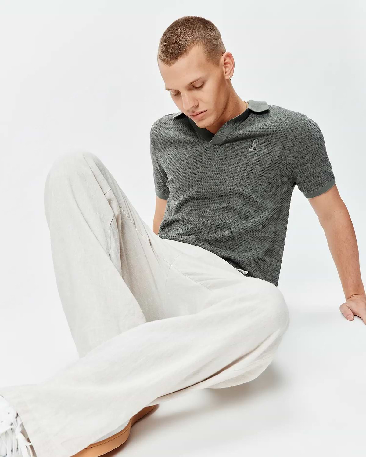 Mens Devon Knit Polo in charcoal green, a classic fit, textured mini-waffle knit fabric, with a small embroidered silver Psycho Bunny skull logo on the left chest.