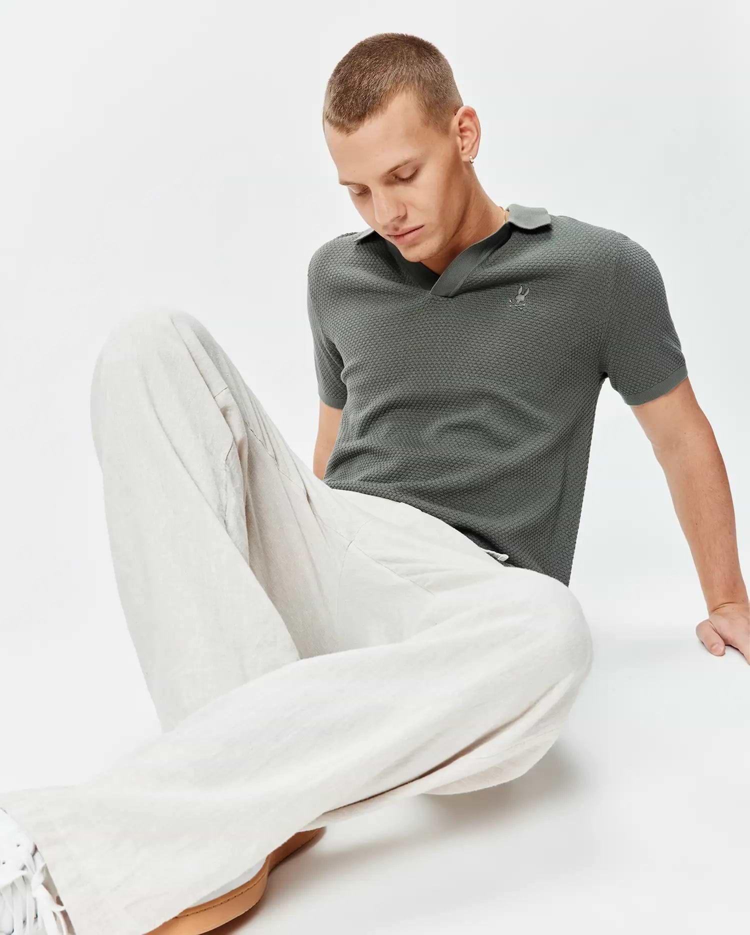 Mens Devon Knit Polo in charcoal green, a classic fit, textured mini-waffle knit fabric, with a small embroidered silver Psycho Bunny skull logo on the left chest.