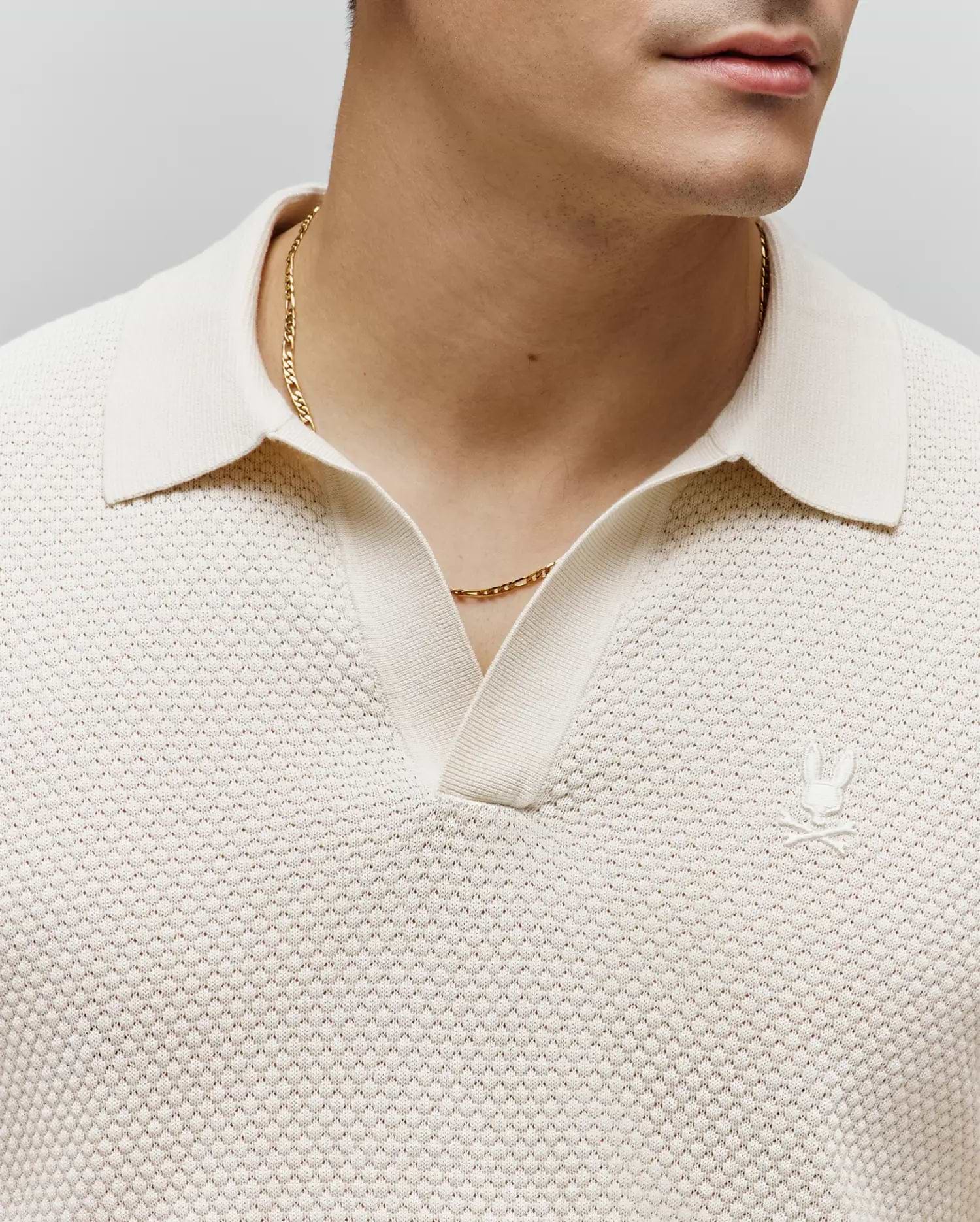 Mens Devon Knit Polo in cream, featuring a textured knit fabric, classic collar, V-neck placket, and a small embroidered cream Psycho Bunny skull logo on the left chest.