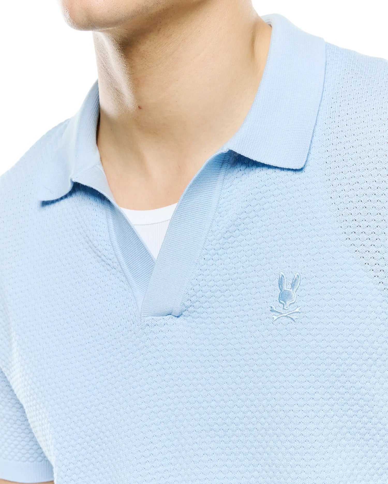 Mens Devon Bubble Stitch Knit Polo in light blue, featuring a unique bubble stitch texture, open placket, and a small, tonal embroidered Psycho Bunny skull logo on the left chest.