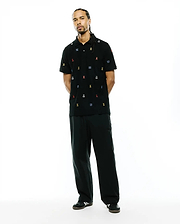 Mens Colin All-Over Pique Polo, a black pique polo shirt with a classic fit, featuring an all-over embroidered pattern of small, colorful Psycho Bunny skull logos and blue wave motifs.
