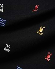 Mens Colin All-Over Pique Polo in black, featuring a classic pique texture with an all-over embroidered pattern of small, colorful Psycho Bunny skull logos in red, yellow, and white, alongside blue wave motifs.