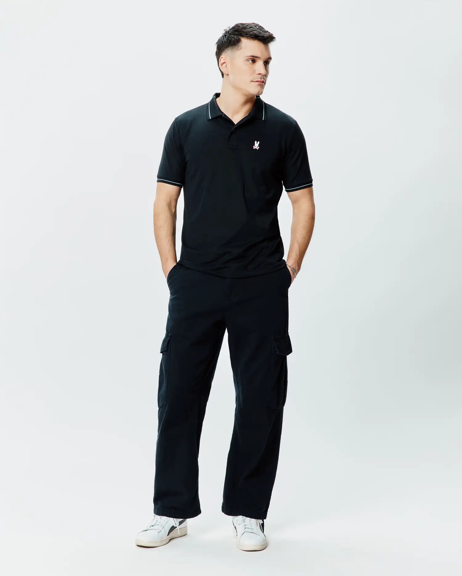 Mens Edwin Sport Polo, black pique knit polo shirt with a classic fit, featuring white piping on the collar and sleeve cuffs, and a small white embroidered Psycho Bunny skull logo on the left chest.
